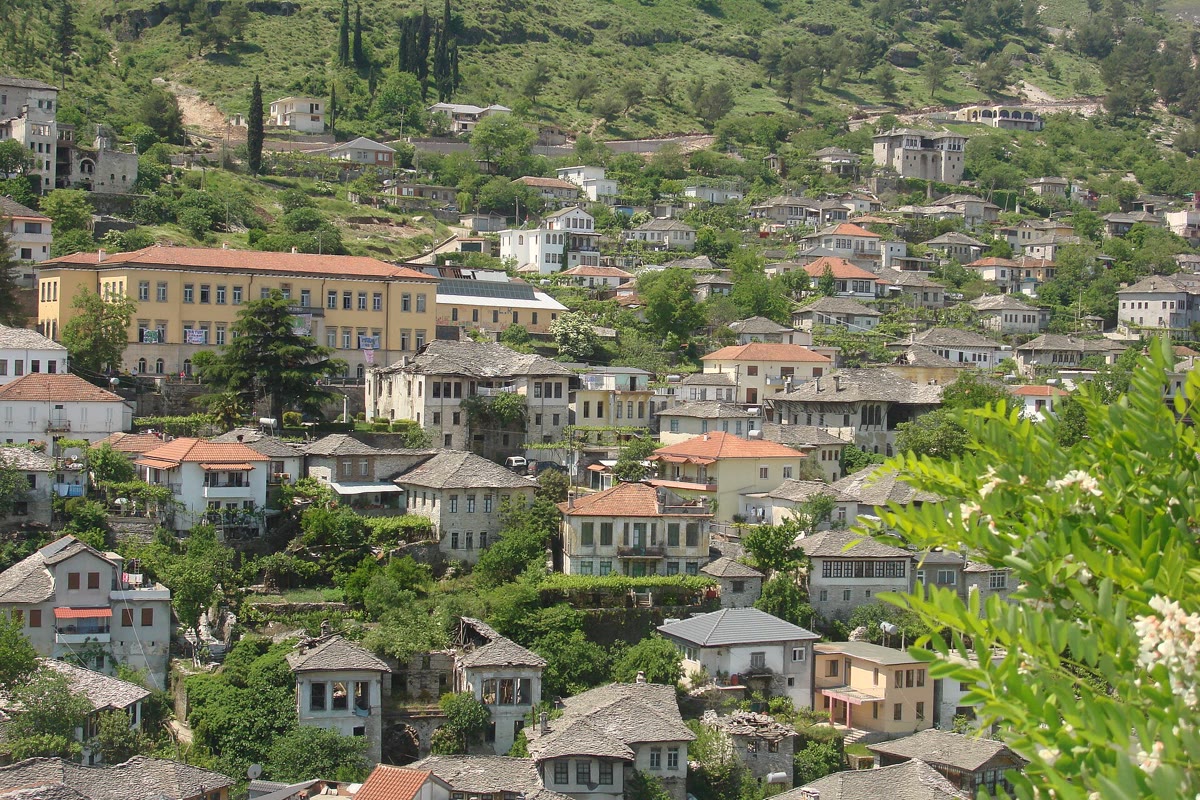 Steinhäuser und Burg der UNESCO-Stadt Gjirokastra vor bergiger Kulisse