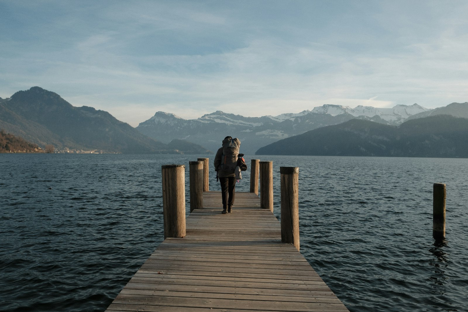 Frau geht über einen Steg Richtung Berge am See