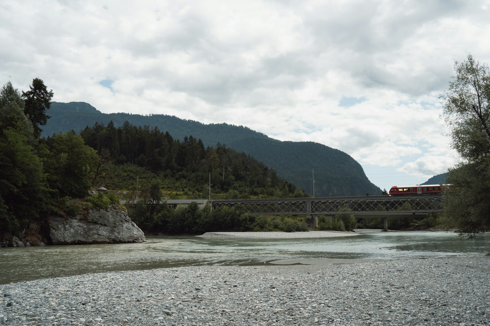Zug überquert eine Brücke zwischen Bergen und Fluss