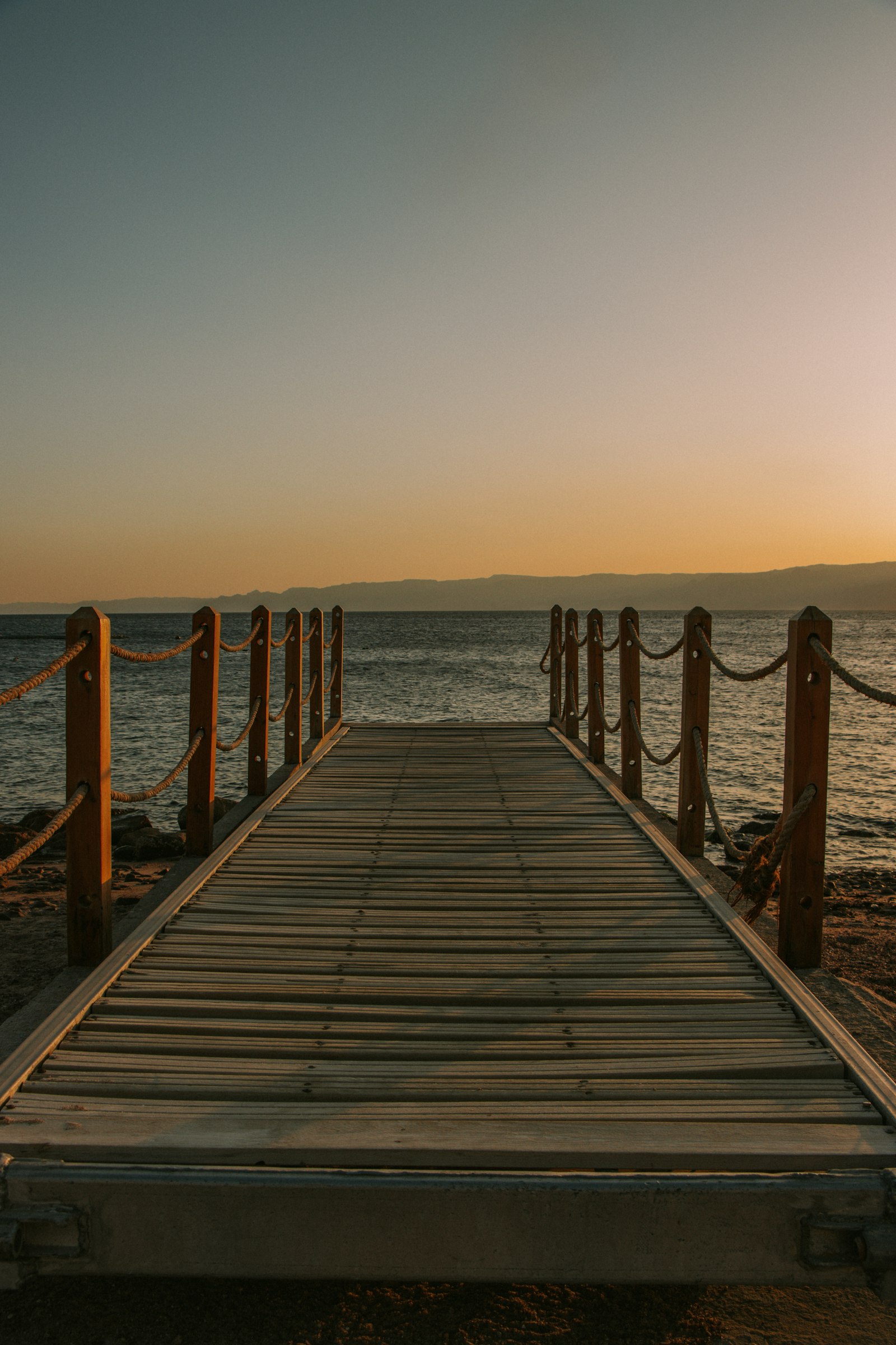 Holzsteg ins Meer bei Sonnenuntergang