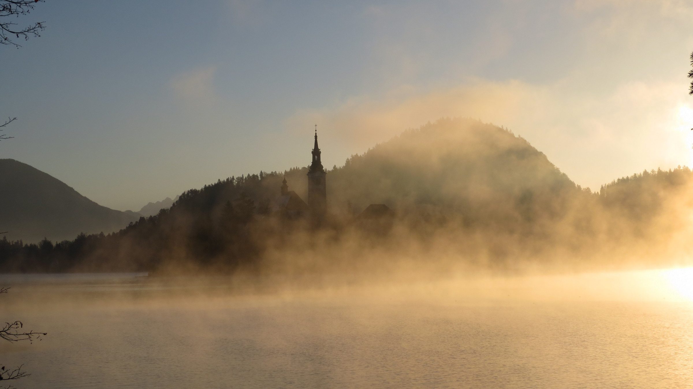 Insel im See von Bled in Slowenien bei nebligem Sonnenaufgang