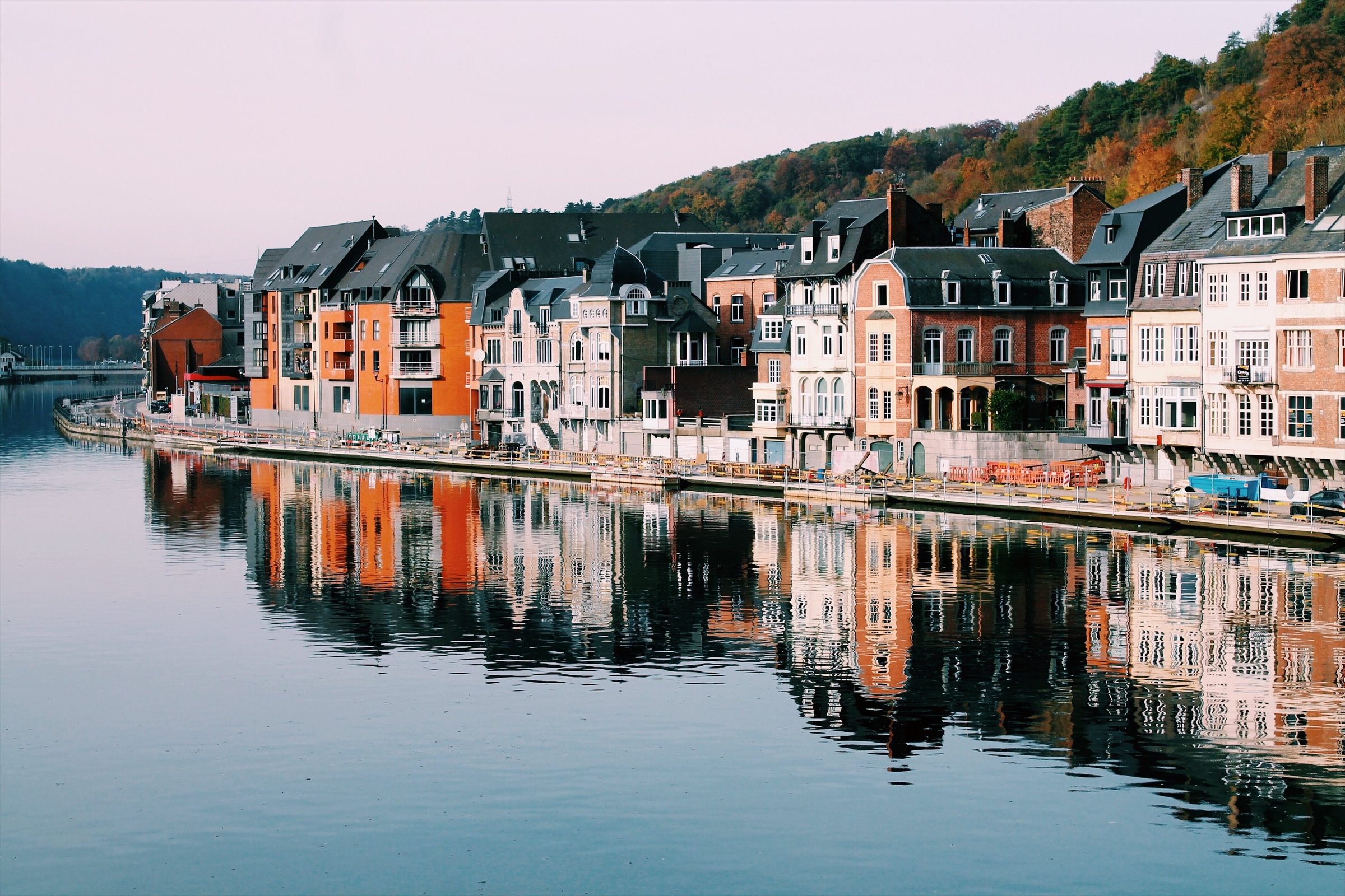 Bunte Häuserzeile an der Maas in Dinant, Belgien, mit Spiegelung im Wasser