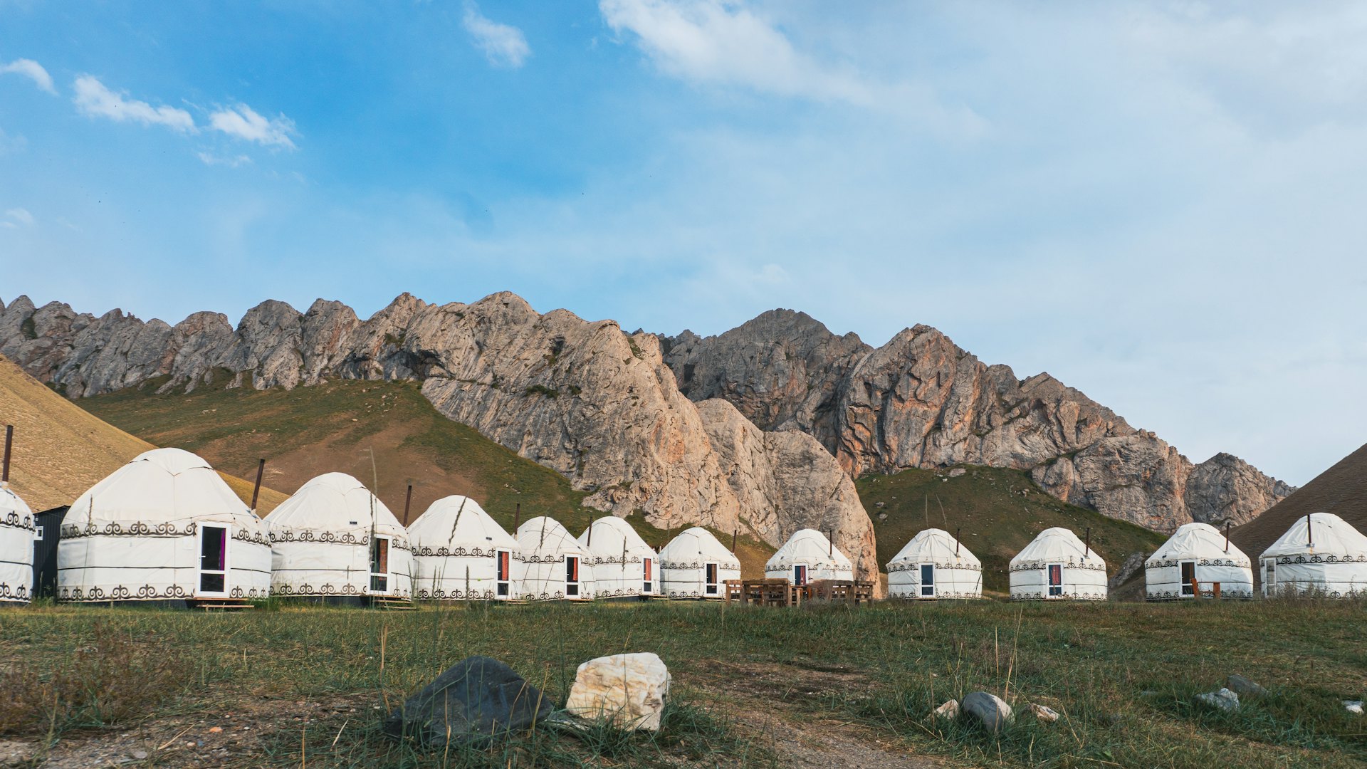 Reihe von Jurten vor Bergkulisse in Kirgisistan